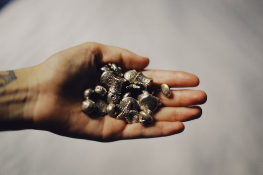 silver and black beads on persons hand