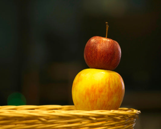 a yellow and red apple sitting on top of a wicker basket