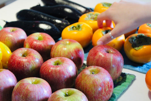 a person reaching for an apple in front of a pile of fruit