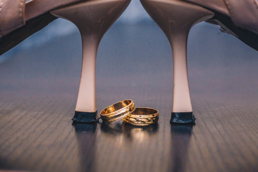 a pair of gold wedding rings sitting on top of a wooden table