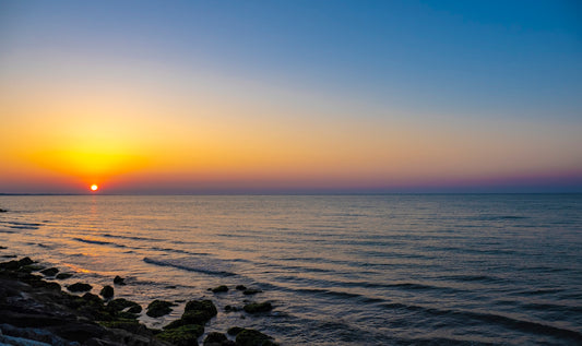 the sun is setting over the ocean on a clear day