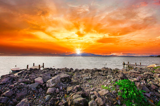 a sunset over a body of water with a boat in the distance