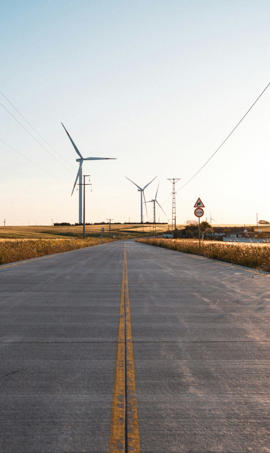 An empty road with wind turbines in the background