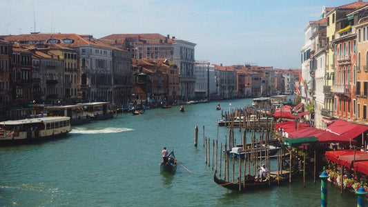 A boat traveling down a river next to tall buildings