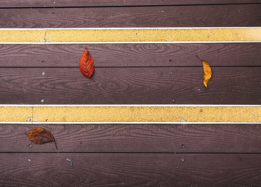 A close up of a bench with leaves on it