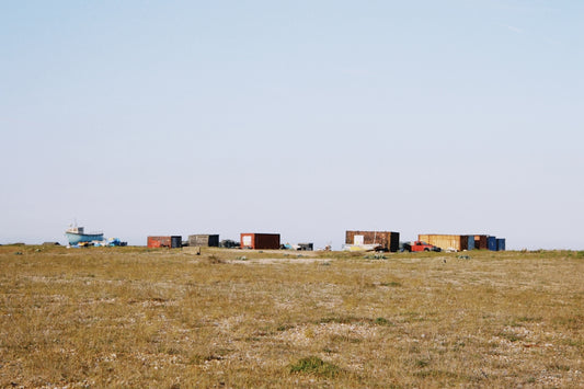 Some buildings sit atop a grassy plain.